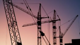 Cranes on an industrial construction site. Photo by Artem Labunsky on Unsplash.