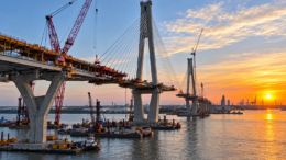 Major bridge construction over water with cranes and cable-stayed spans
